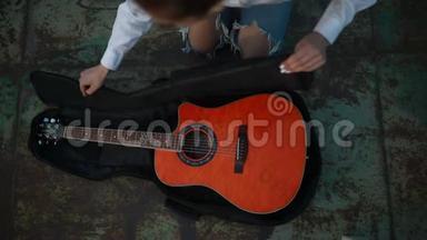 女孩把吉他放在箱子里，拉链锁。