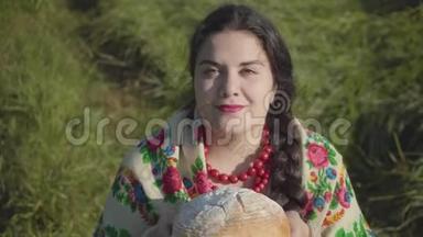 <strong>可爱</strong>的<strong>超</strong>重女人坐在草地上嗅着美味的面包准备吃的肖像。 传统观念。 国家