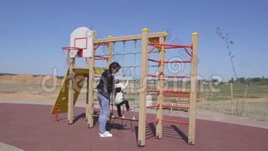 3岁的白种人小女孩和她的母亲在一个现代化的儿童游乐场玩耍，运动器材