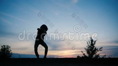 一个年轻人在夕阳下跳迪斯科，他的身影清晰可见，动作缓慢