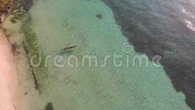 一个人的无人机镜头是在日出时沿着绿松石水从沙质海岸划艇。 电影院俯视图