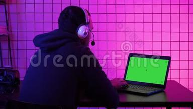 专业玩家在他的笔记本电脑上玩电子游戏。 绿色屏幕模拟显示。