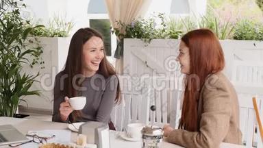 两个年轻女孩边看边喝茶，在午餐时慢动作愉快地交谈
