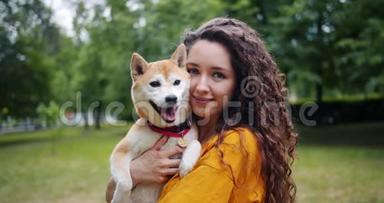 美丽的女孩可爱的狗<strong>主人</strong>站在公园里和她美丽的<strong>宠物</strong>微笑的肖像