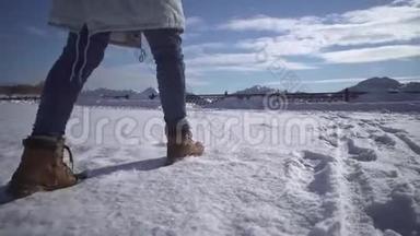 女人`穿着米色靴子在雪地里行走