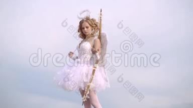 小丘比特用爱的箭瞄准某人。 天真的女孩，有天使的翅膀，站着弓箭