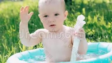一个夏天，小男孩正在游泳，玩着在<strong>充气</strong>游<strong>泳池</strong>里溅起的水花