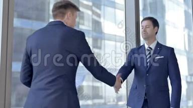 两位中年商人在办公室里看文件和握手