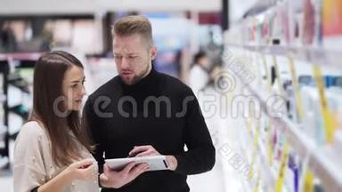化妆品店里的年轻男女看着数码平板电脑说话