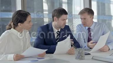 执行公务人员通过办公室桌上的文件讨论事情