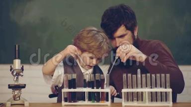 爸爸和他的小儿子老师和小学生在课堂上使用试管。 男老师和学龄前儿童一起玩。 爸爸