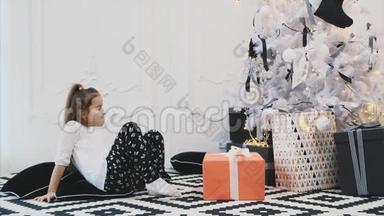 漂亮的孩子很高兴也很惊讶能得到圣诞节最大的礼物，现在她试着拿起这个盒子，但它是