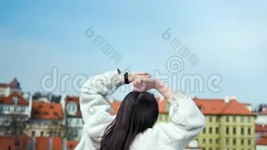 背景图片：快乐的旅行女孩跳跃和挥动双手快乐的典型欧洲城市