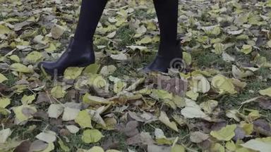 落叶开始了。 一个女人在秋天公园的落叶上散步