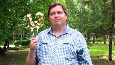 大个子拿着金色气球，把13号放在户外。 13周年庆祝晚会