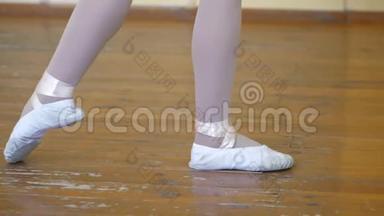 在芭蕾训练期间，<strong>一个</strong>穿白色芭蕾舞鞋的女孩`在<strong>一个</strong>旧木<strong>地板上</strong>的腿特写。 古典元素