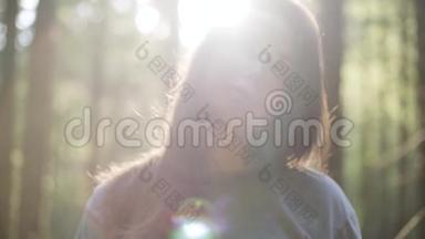 美丽的女人在绿色的森林里站在阳光下望着<strong>远方</strong>的肖像。 那个女孩在森林里徒步<strong>旅行</strong>