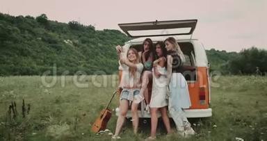 房车在大自然的中间，一群美丽的女士在自拍，坐在面包车的背面，快乐