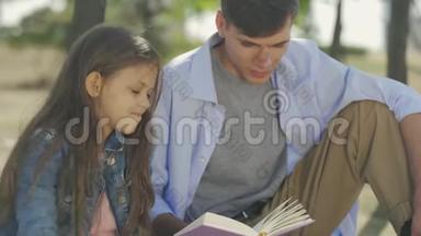 小男孩和小妹妹在阳光明媚的秋天，坐在公园里看诗或故事的书
