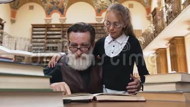 聪明的老胡子爷爷戴着眼镜看书，和他可爱的小孙女在图书馆的桌子上
