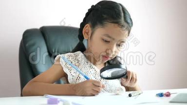 小亚洲女孩用放大镜做家庭作业，用快乐微笑教育理念选择焦点浅野深度