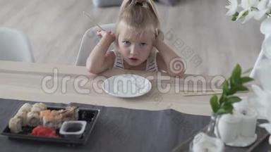 小女孩试图在家里用筷子吃<strong>寿司</strong>。