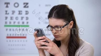 戴眼镜的女人在智能手机上打字，现代技术，小字体