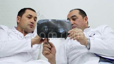 两位牙医用下巴`x光来讨论病人的治疗方案。