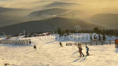 一群滑雪者和滑雪者在夕阳和山峦的映衬下走下滑<strong>雪坡</strong>