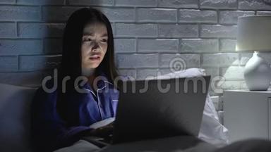 女人躺在床上，匆忙地用笔记本电脑工作，试图赶上最后期限，加班加点