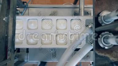 现代设备将酸奶倒入容器中。 生产和包装食品和饮料的自动化设备。