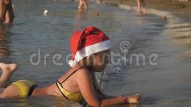 戴着红色圣诞帽的小<strong>可爱女孩</strong>在海滩上玩得很开心。