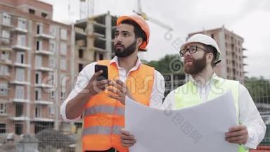 建筑商和建筑师在施工现场用手机拍照，并与施工计划核对。