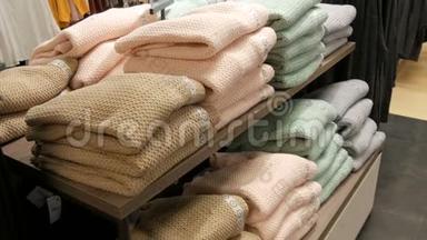 在<strong>服装</strong>店的<strong>货架</strong>上，一排叠在一起的浅色的漂亮温暖的女士针织毛衣