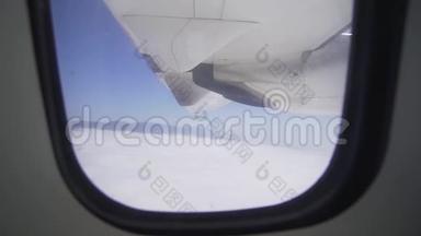 窗外的景色-一个飞机机翼和一个涡轮发动机在云层上方飞行。 空运