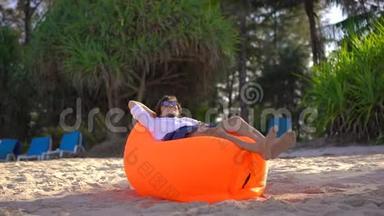 热带海滩上的年轻人躺在<strong>充气</strong>沙发上，他刚刚<strong>充气</strong>。 暑假概念