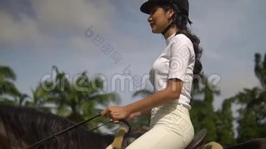 在阳光明媚的日子里，穿着黑色头盔和白色T恤骑着马的漂亮年轻女人是缓解压力的最佳方式