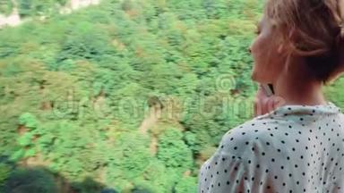 在奥<strong>卡</strong>特峡谷的桥上，一位金发的年轻女子穿着浅白的波尔<strong>卡</strong>多上衣，<strong>通过</strong>电话交谈，拍摄
