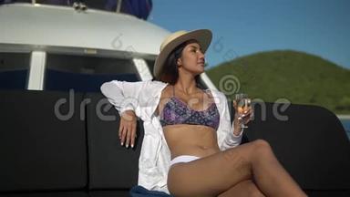 可爱的年轻<strong>女士</strong>，戴着草帽，穿着<strong>比基尼</strong>，坐在一艘很棒的游艇上，喝着香槟和日光浴，享受着快乐