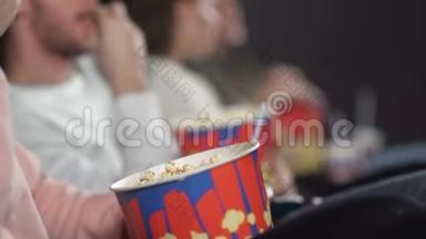 在电影院看电影的朋友喝可乐吃爆米花。