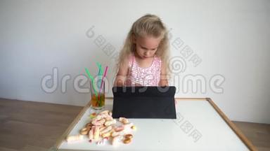 四岁的金发小孩在看平板电脑。 快乐的电脑迷妹