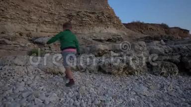 小男孩爬上海边的岩石，小男孩追着狗。