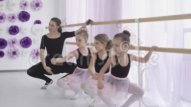 集中注意力的女孩在<strong>舞蹈</strong>学校学习基本的芭蕾姿势，<strong>老师</strong>细心地帮助她们掌握