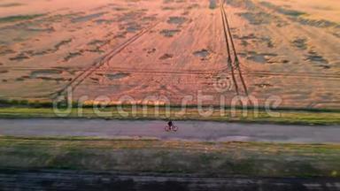 日落时分，一个人骑着自行车沿着黄色的麦田，沿着绿色的田野