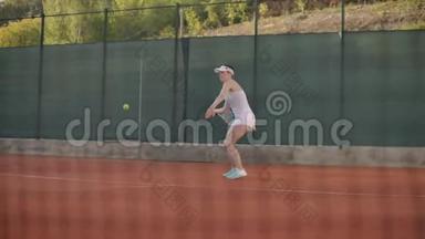 女网球运动员在球场上打一个飞球，一个动态的网球游戏在球场上开放。