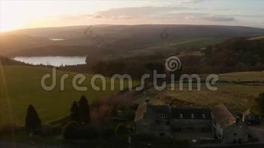 日落时分，在绿油油的英国乡村，一座古老农舍的空中镜头