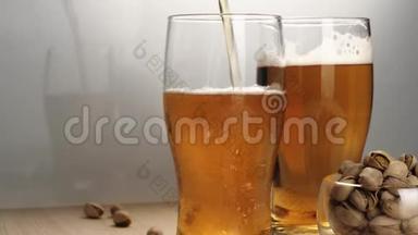 新鲜啤酒。 在白色背景的木桌上，用手将美味的冰镇啤酒和一些开心果倒入啤酒杯碟中