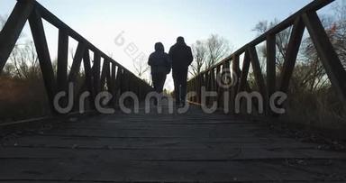 秋天，在湿地环绕的自然公园里散步的女孩和男孩。 这条小路是由一条背景为b的木制长廊构成的