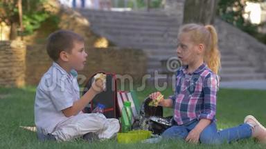 学生们在校园里坐在草地上吃三明治，喝饮料