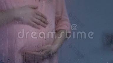 孤独的孕妇在雨窗后抚摸着大肚子，心情沮丧